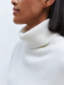 Close-up detail of a classic white turtleneck knit sweater, soft texture for autumn winter.