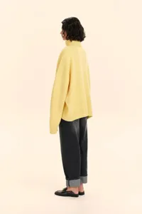 Detail view of women's yellow turtleneck knitted sweater, soft fabric and comfortable loose fit style.