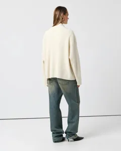 Detailed view of women's ribbed high-neck knit sweater paired with vintage blue denim jeans.