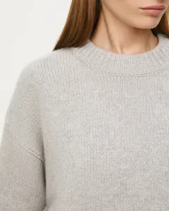 Close-up of a cozy light gray knit crewneck sweater detail, showing soft texture and collar.