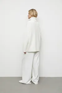 Vue détaillée d'un pull-over en tricot blanc à col roulé et pantalon sur un modèle.