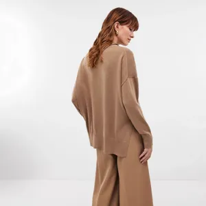 Detail view of a women's camel loose-fit knit sweater featuring a stylish side slit hem.