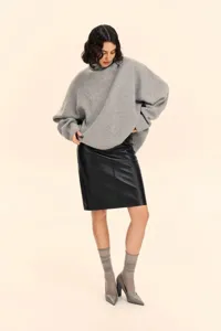 Detailed shot of an oversized grey turtleneck sweater paired with a stylish black leather skirt.