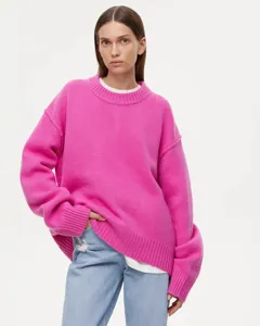 Detail shot of a bright pink oversized crewneck knit sweater worn with denim jeans.