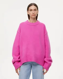 Close-up detail of a bright pink oversized knit sweater featuring a classic crew neck design.