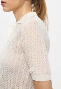 Cream knit polo shirt short sleeve detail view showing delicate texture and classic collar.