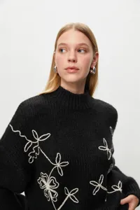 Black mock neck knitted sweater featuring elegant white floral embroidery details stylish.
