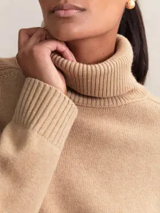 Close-up of cozy camel turtleneck sweater showcasing fine knit texture and ribbed cuff.