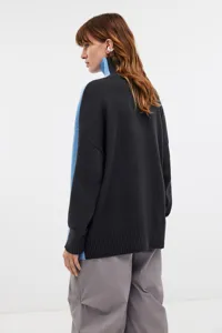 Detail view of back and side of oversized two-tone knit turtleneck sweater in black and blue.
