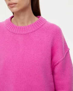Close-up detail view of bright pink knit sweater showcasing textured fabric and crew neckline.