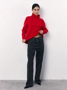 Detailed view of the stylish red turtleneck sweater paired with casual dark grey loose denim jeans.
