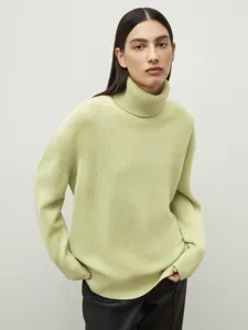 Close-up view of soft lime green turtleneck knitted sweater featuring ribbed cuffs.