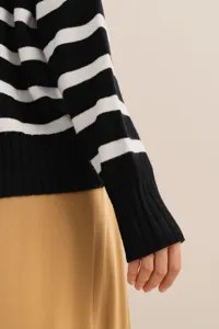 Close-up detail of a classic black and white striped knit sweater sleeve and skirt.