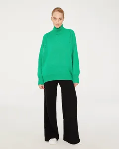 Green turtleneck sweater detail view showing soft knit texture and comfortable relaxed fit.