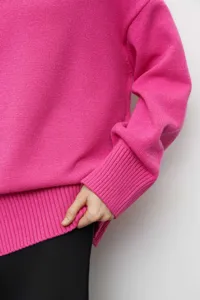 Gros plan détaillé de la manchette et de la texture côtelée d'un pull en maille rose vif.