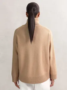 Back view of camel turtleneck sweater showing soft knit texture and ribbed hem detail.