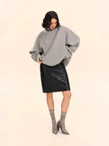 Women's grey oversized turtleneck knitted sweater paired with a chic black leather skirt for winter.