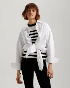 Detailed view of women's black and white striped knit sweater layered with a white shirt.