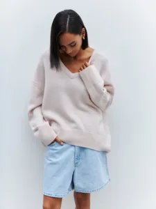 Casual oversized V-neck long sleeve knit sweater in soft light pink matched with denim shorts.