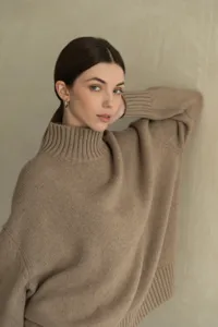 Close-up detail of women's casual oversized turtleneck knit sweater in beige, soft texture.