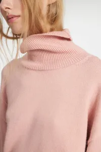 Pink turtleneck knit sweater detail closeup, soft fabric, cozy winter fashion style top.
