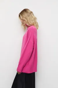 Vue de détail latérale d'un pull col roulé oversize rose vif avec texture tricot.