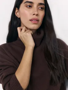 Detailed shot of a brown turtleneck sweater on a model, highlighting soft knit fabric.
