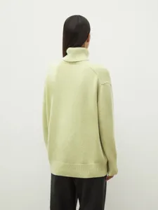 Detail view of a women's casual loose turtleneck knitted sweater in light green color.