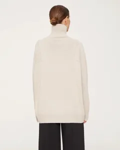 Detailed back view of a cozy beige turtleneck sweater showcasing its soft knit texture and ribbed hem.