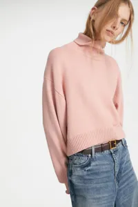 Detailed view of the soft pink turtleneck sweater featuring a cozy loose fit and cropped design.