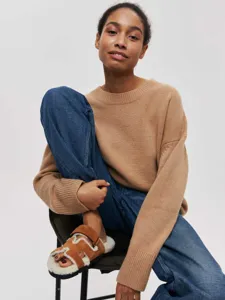 Detail shot of a cozy camel crewneck knit sweater worn in a casual lifestyle setting.