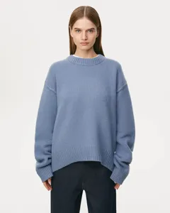 Detail view of a cozy light blue crewneck knitted sweater worn by a model, soft texture.