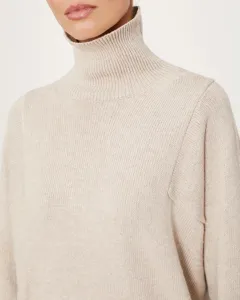 Close-up of cozy knit turtleneck sweater in soft oatmeal, featuring ribbed collar and texture.