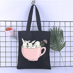 Detail view of a black canvas tote bag featuring a cute rabbit teacup print, perfect for daily use.
