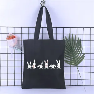 Black canvas tote bag detail view, cute rabbit print design, casual student handbag.