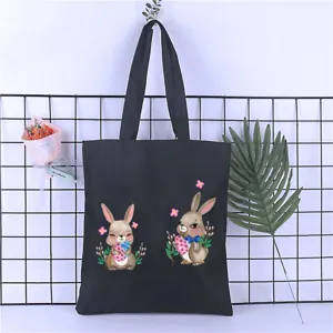 Black canvas tote bag detail featuring cute cartoon bunny watercolor illustration and floral.