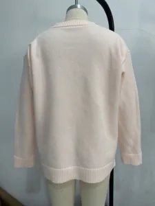 Pink knit sweater detail showing soft ribbed crewneck and cuffs, cozy autumn pullover.