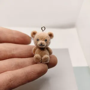 Close-up detail shot of a cute miniature flocked teddy bear charm for DIY jewelry making accessories.