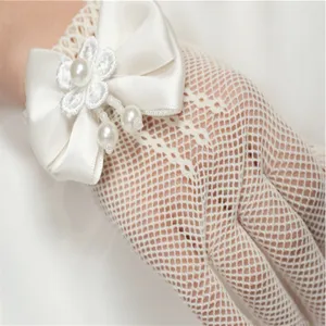 Close-up detail of white lace mesh gloves featuring a satin bow and pearl pendants.