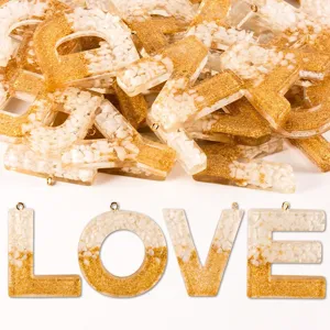 Resin alphabet letter charms with gold glitter and stones for DIY jewelry keychains.