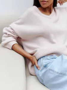 Close-up of a cozy V-neck knit sweater in light pink, featuring long sleeves and relaxed fit.