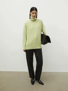 Detailed view of the light green turtleneck sweater showing its cozy knit fabric and relaxed fit.