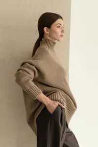 Detail shot of a cozy beige high-neck knit sweater, showing soft texture and ribbed collar.