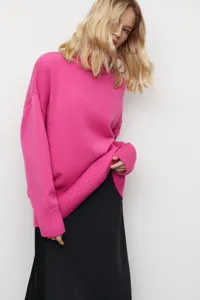 Gros plan détaillé d'un pull en tricot rose vif à col montant avec des finitions côtelées.