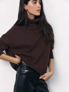 Women's autumn winter brown turtleneck loose knit sweater paired with black leather pants.