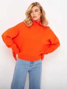 Close-up detail shot of a bright orange oversized turtleneck sweater worn by a fashion model.