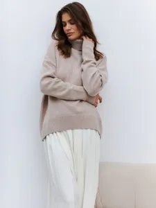 Detailed view of women's cozy beige turtleneck sweater featuring a loose fit and soft knit fabric.