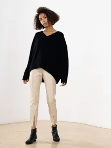 Casual black v-neck long sleeve sweater paired with beige faux leather pants for women.