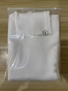 Detailed view of folded white turtleneck sweater in protective packaging, soft knit fabric.