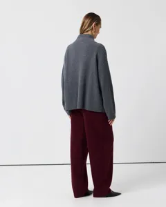 Back view of a women casual ribbed mock neck sweater paired with loose burgundy trousers.